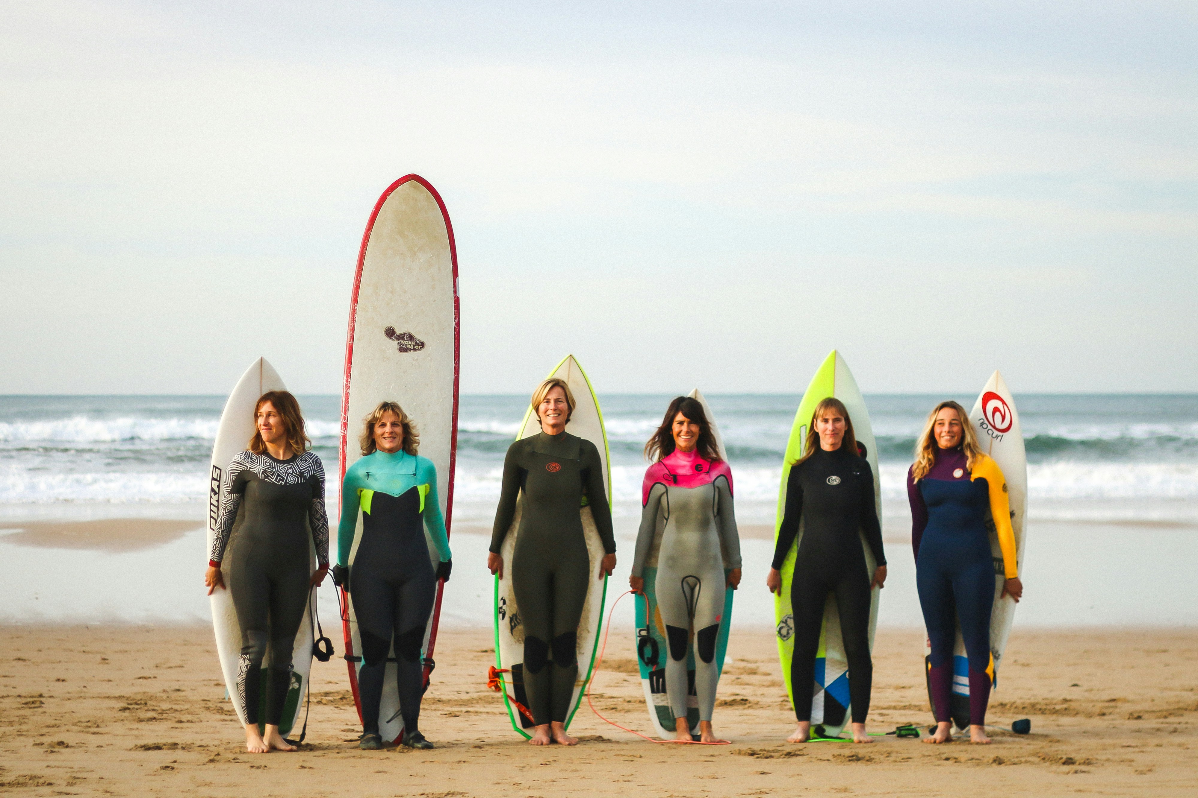 Six women surfers on the beach with their boards