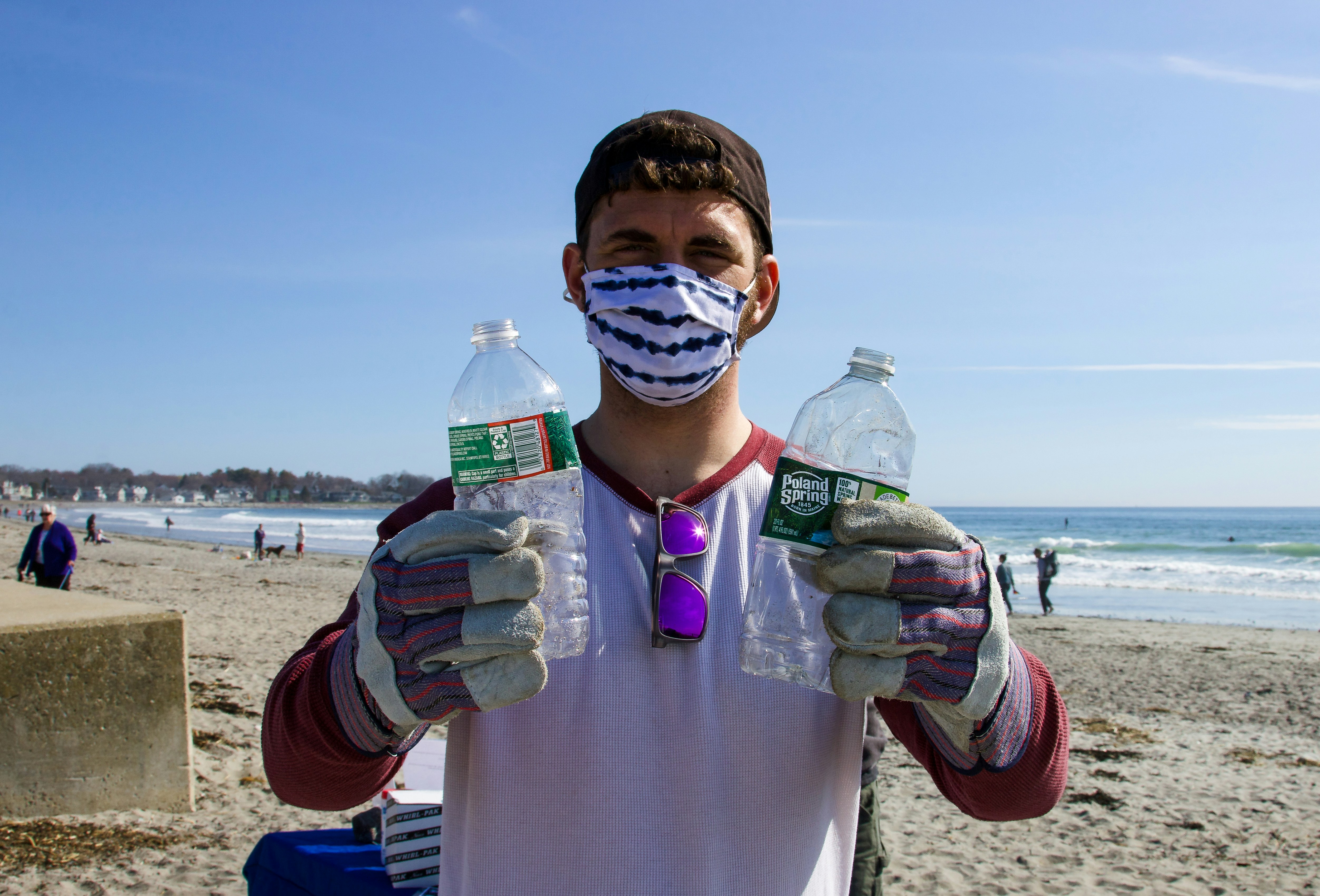 Surfer doing a beach clean-up holding plastic bottles