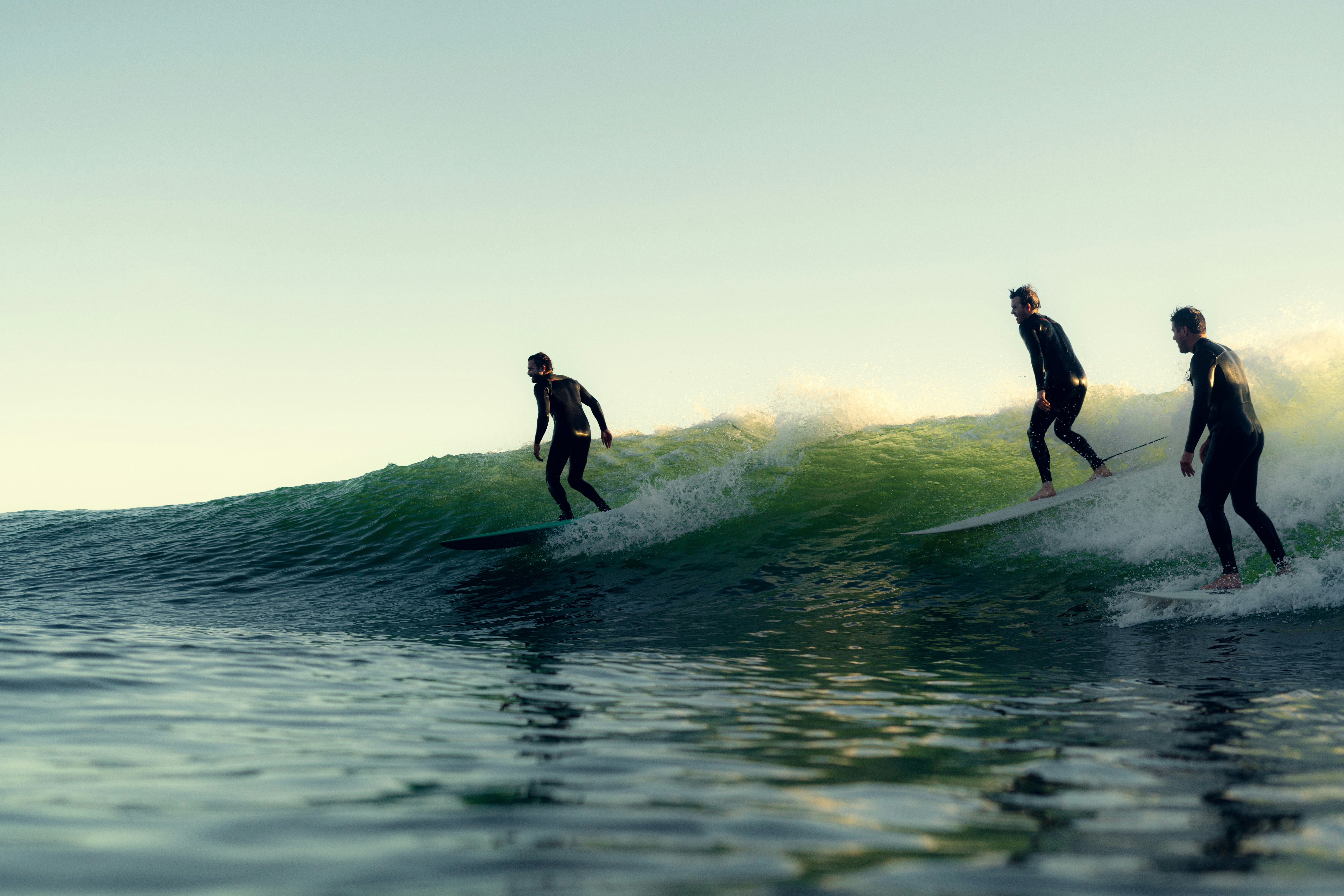 Three surfers riding the same wave
